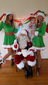 Santa with cheerful elves and child